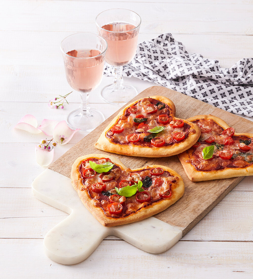 Kleine Pizzen in Herzform mit Tomaten und Oliven