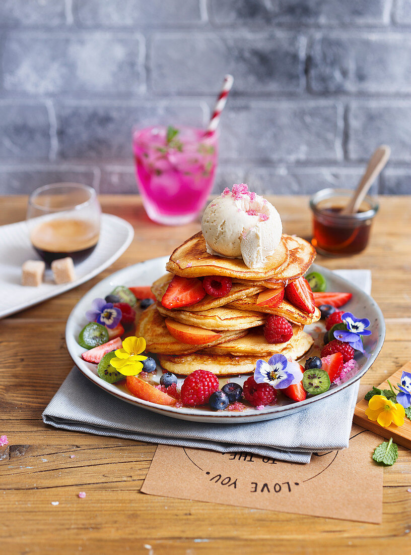 Fluffy pancakes with fresh berries, ice cream and edible flowers