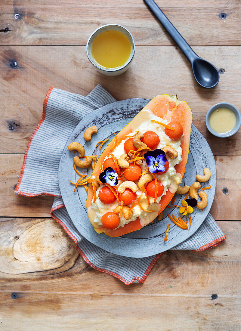 Papaya with orange rice pudding, cashew nuts and edible flowers