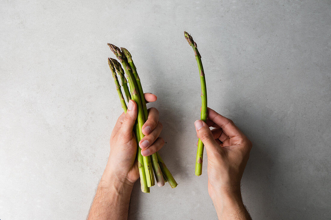 Hände halten grünen Spargel