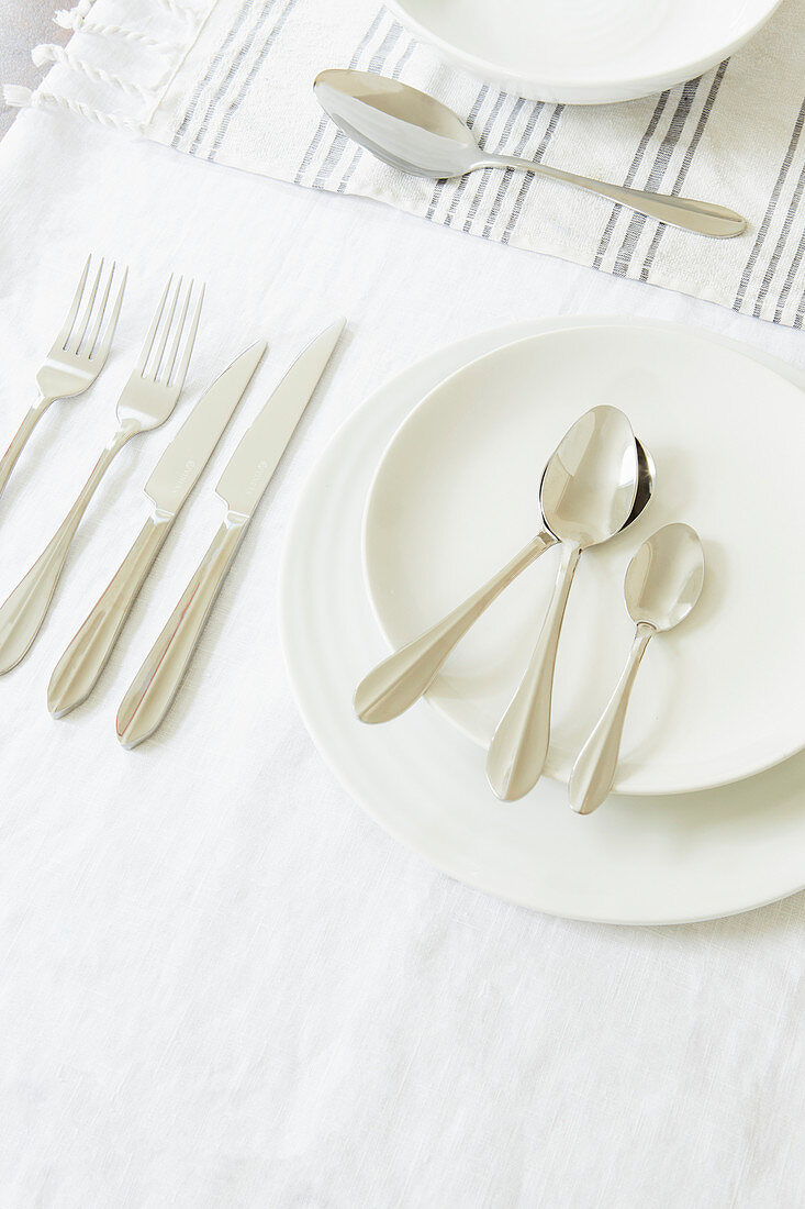 Weisse Teller und Besteck auf Tischtuch