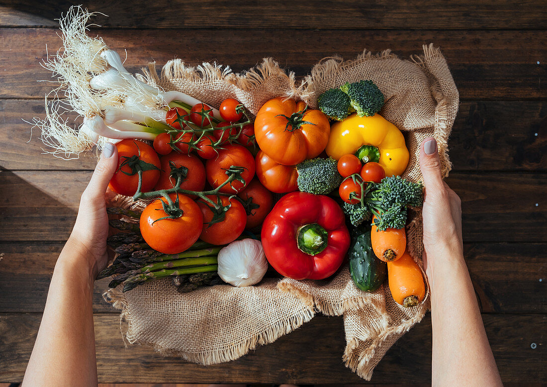 Wooden box with fresh multicolored vegetables and herbs on wooden rustic floor