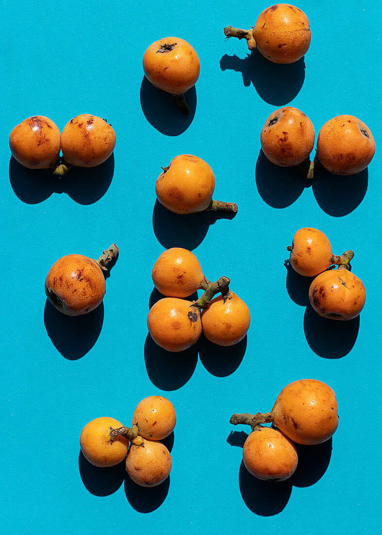 From above ripe medlar fruit placed on colorful blue background