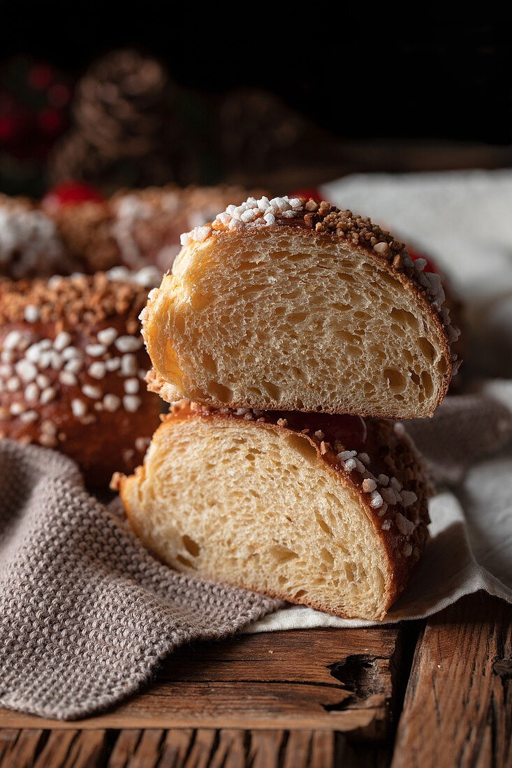 Homemade round bread with hole decorated with sprinkles and cherry placed on wooden table with Christmas decoration