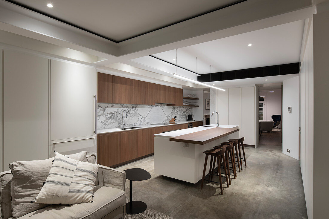 Fitted kitchen, living area and ceiling spotlights in open-plan interior