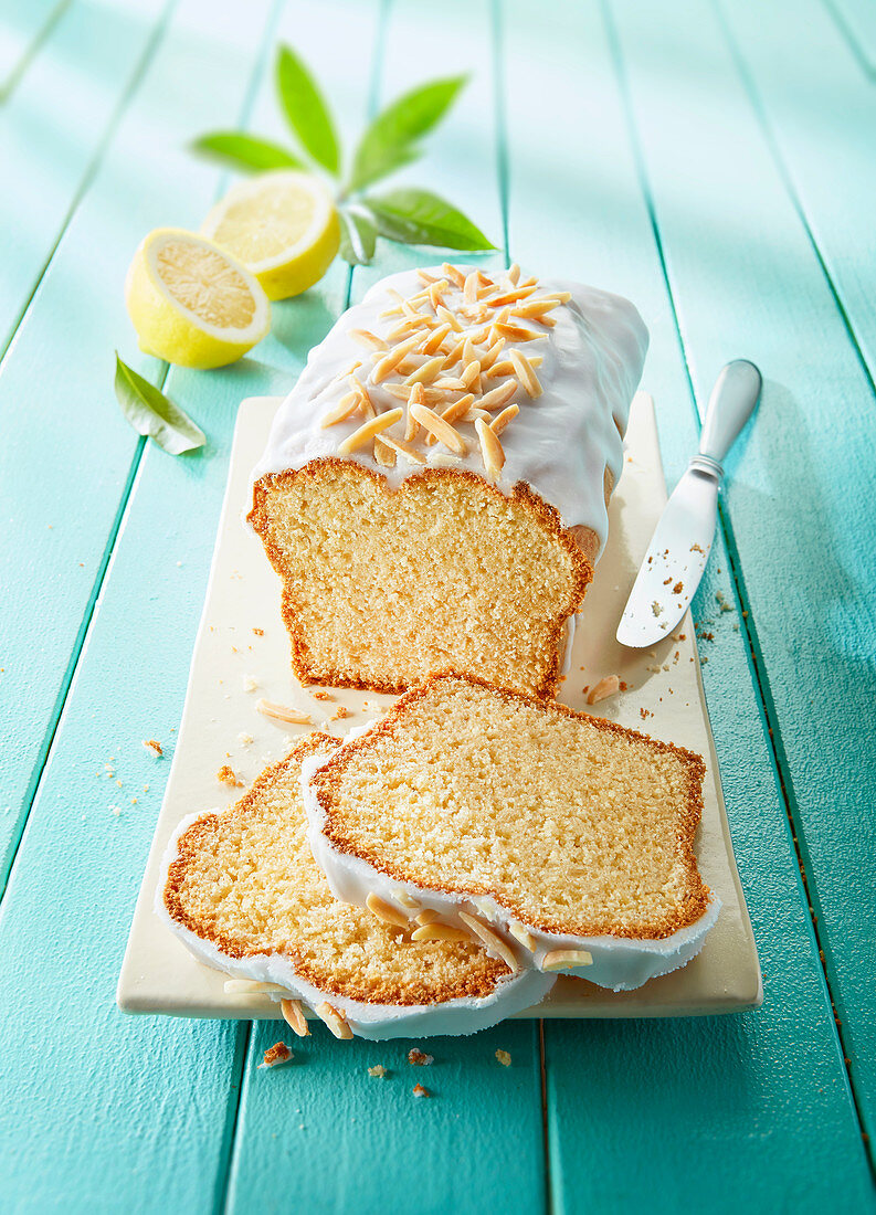 Lemon cake with icing and almond nibs, sliced