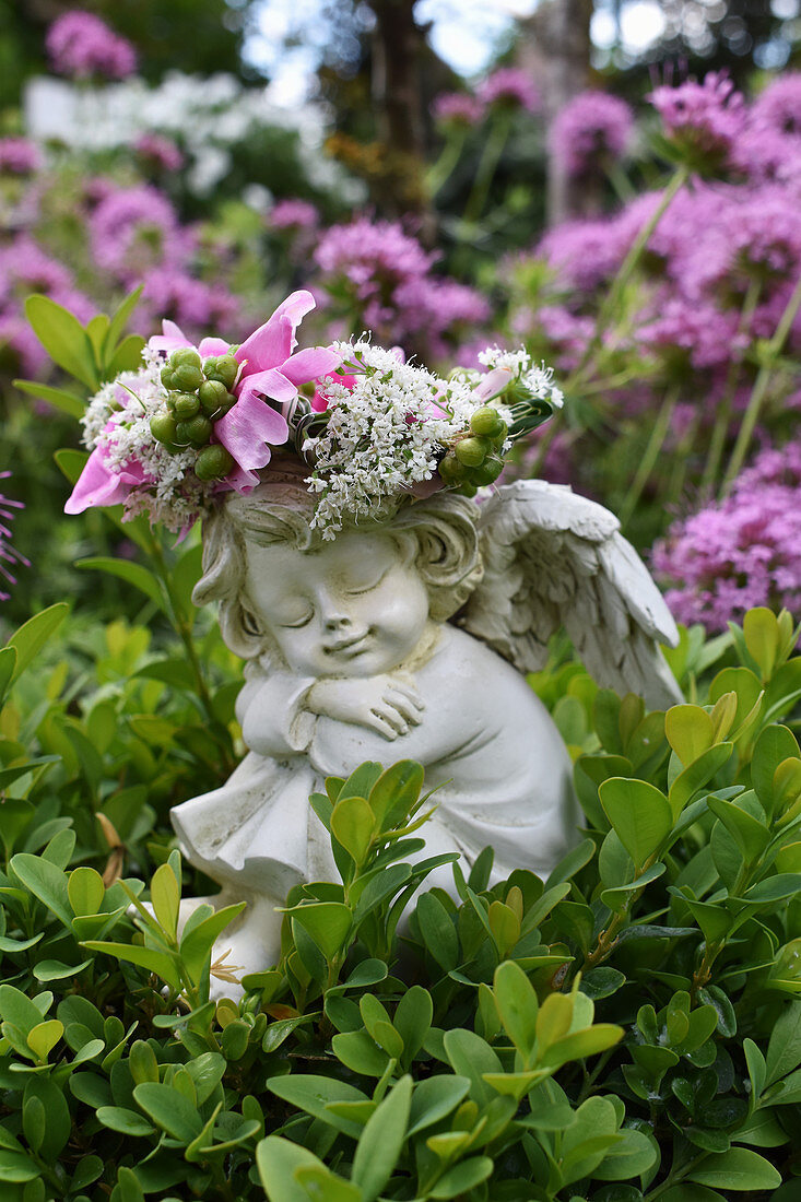 Engelchen mit Blumenschmuck im Buchsbaum