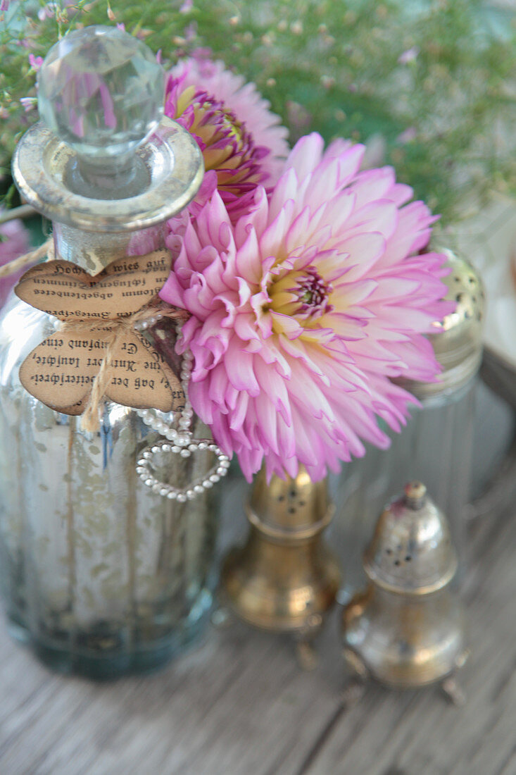 Dahlienblüten als Dekoration mit Bauernsilber und Flasche