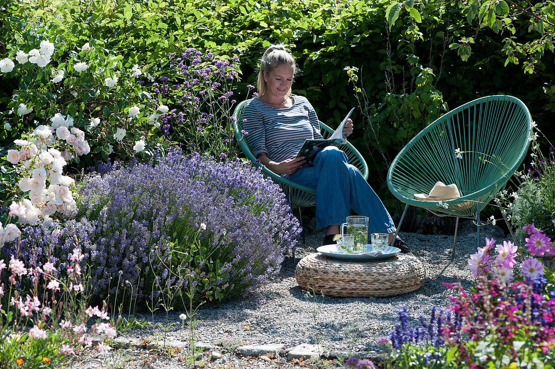 Frau entspannt sich im Garten neben Lavendel und Rosen