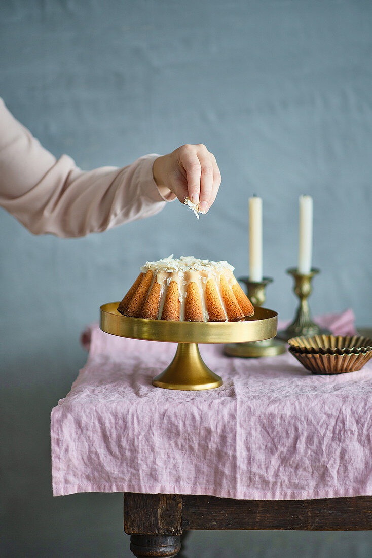 Festlicher Kokos-Kranzkuchen mit weißer Schokoglasur und Mandeln