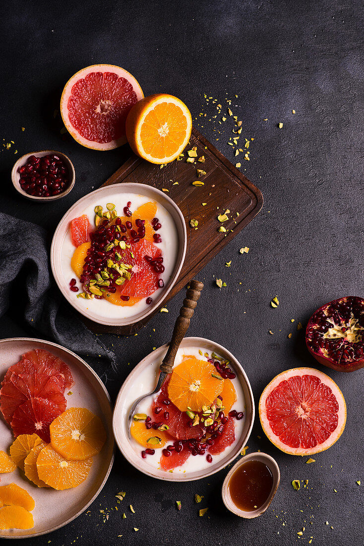 Bowls of natural yoghurt, oranges, grapefruits, pomegranate, seeds and pistachios