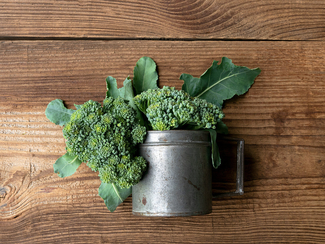 Fresh broccoli in a metal vessel on a wooden background