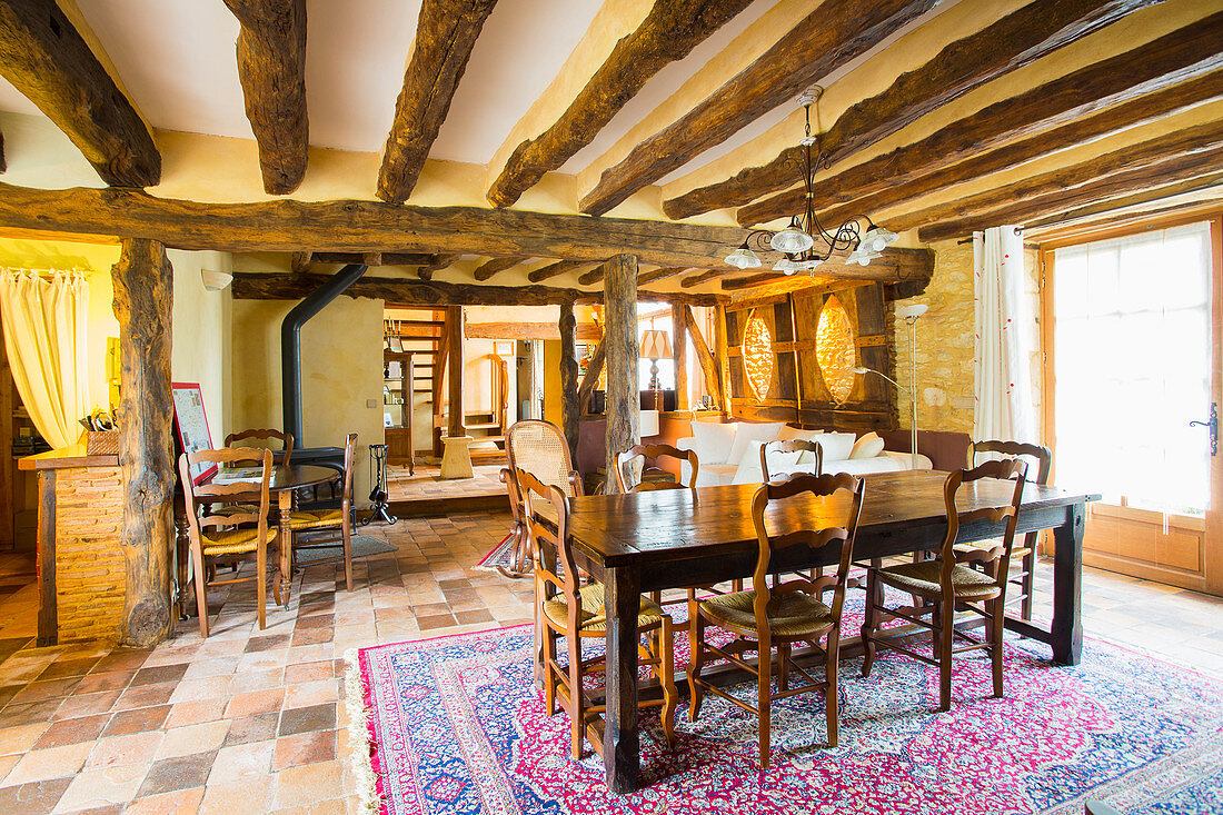 Dining area in open-plan interior with rustic wood-beamed ceiling