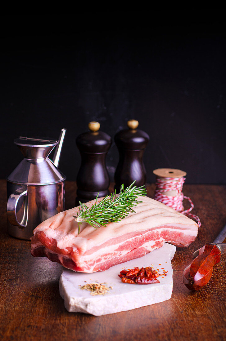 Piece of pork belly with a sprig of rosemary