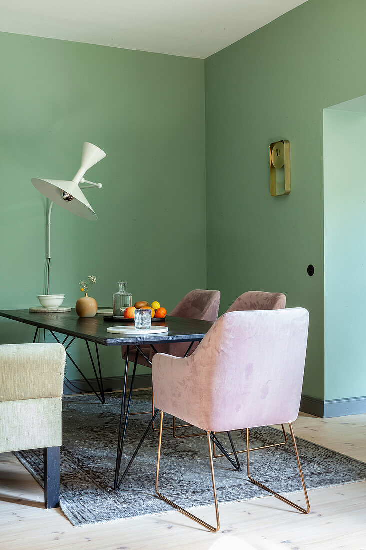 Elegant armchairs around dining table in dining area with green walls