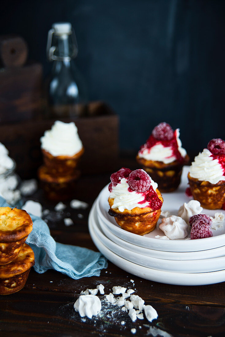 Mini cheesecakes with whipped cream, raspberry sauce and frozen raspberries