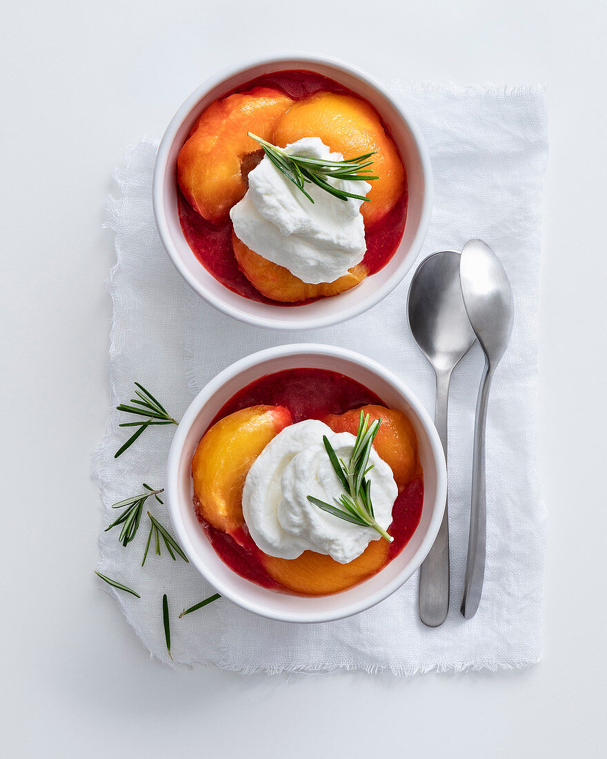 Poached peaches in raspberries sauce with cream and rosemary