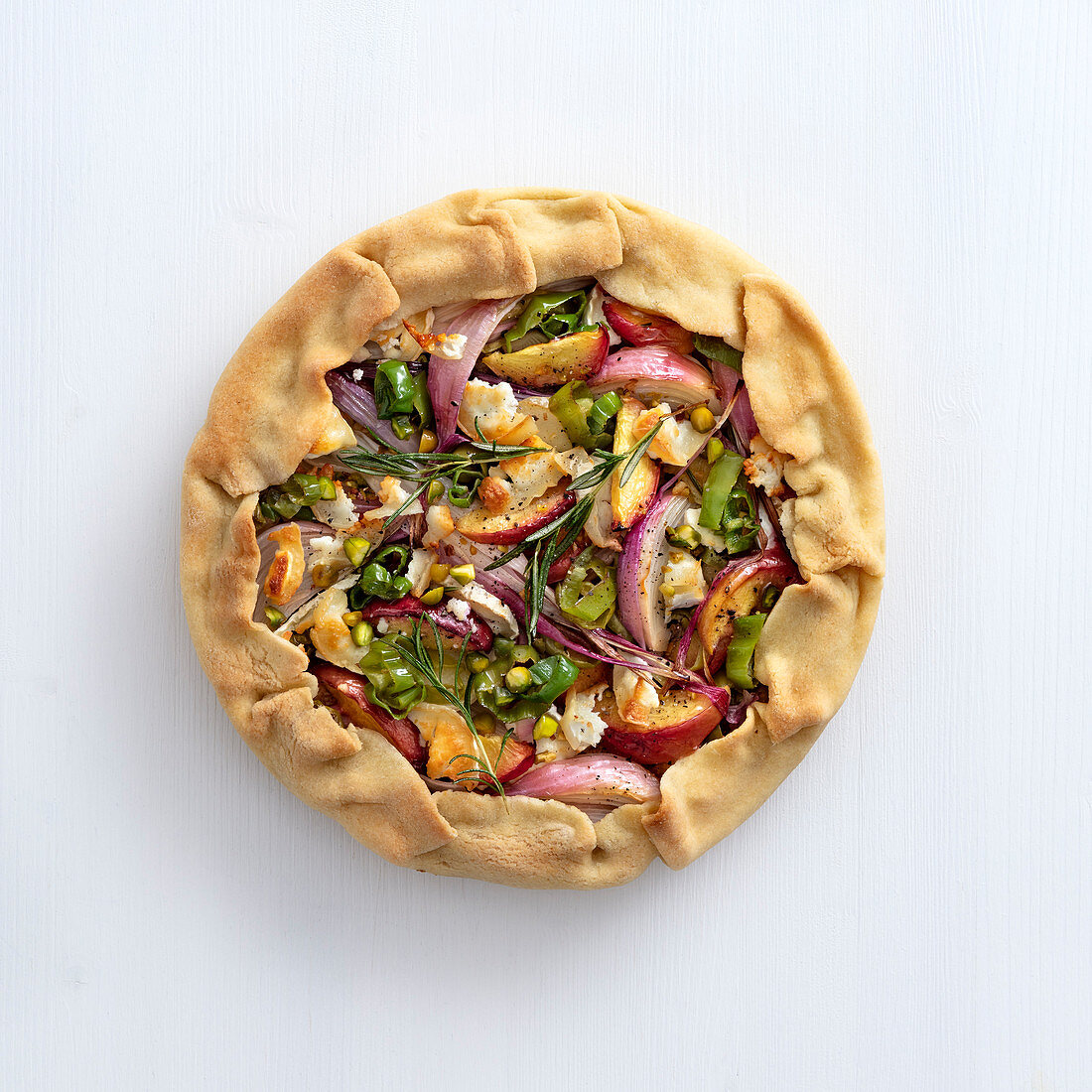 Onion tart with peaches, rosemary, goat's cheese and pistachio nuts