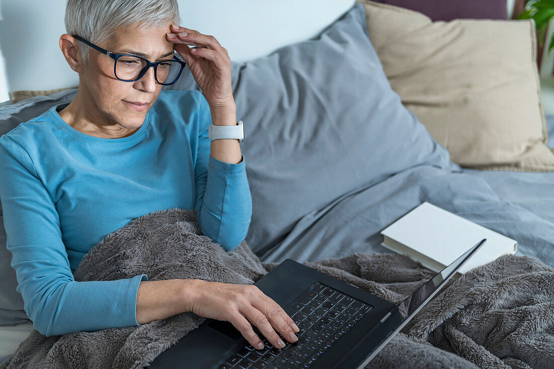 Woman using laptop computer in bed