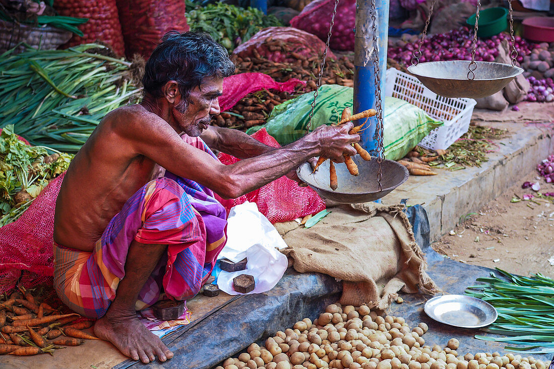 A vendor at a vegetable stall at a market in Sri Lanka