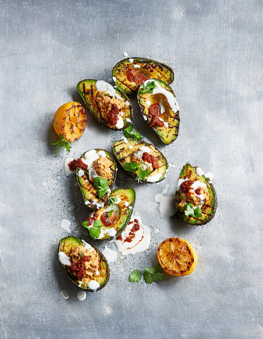 Grilled avocado halves with harissa, hummus and tahini yogurt