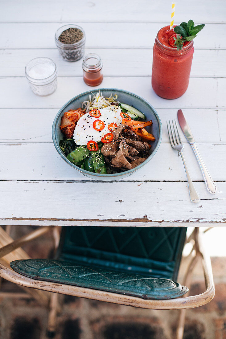 A beef bowl with vegetables, bean sprouts and fried egg