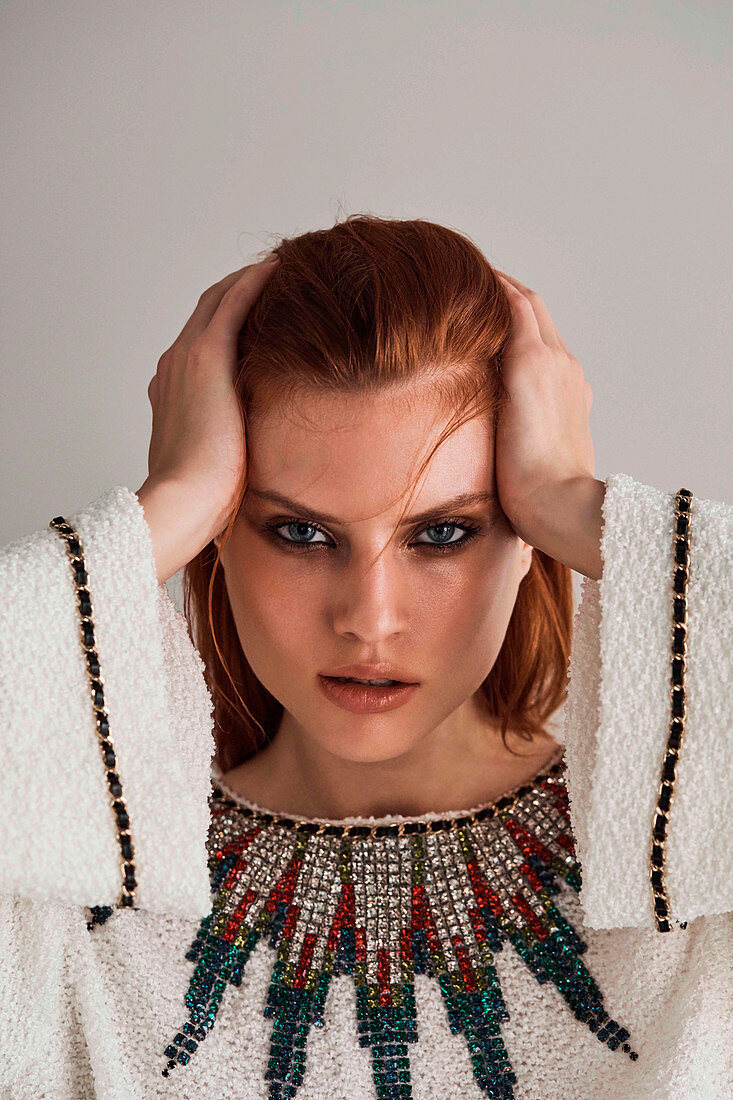 A red-haired woman wearing a white designer dress embroidered with rhinestones