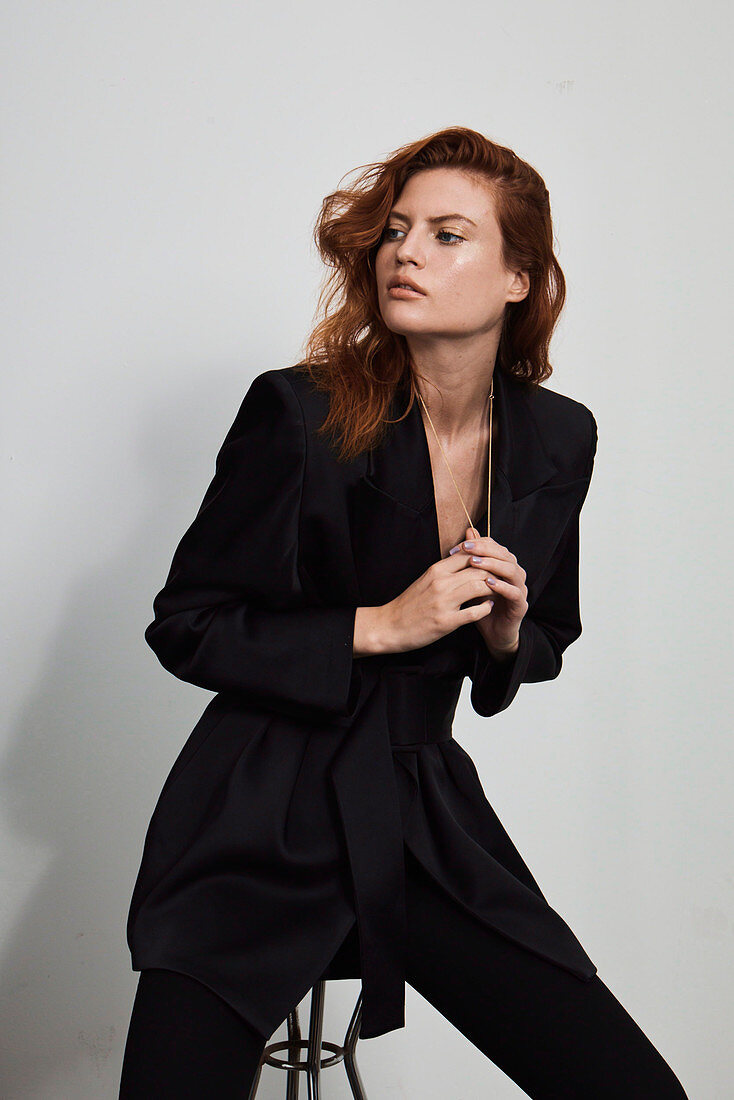 A red-haired woman wearing a black blazer and trousers