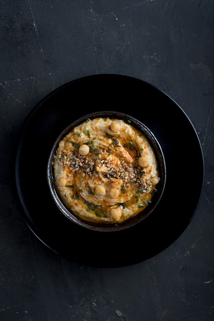 Top view of Delicious homemade hummus with paprika, seeds and olive oil