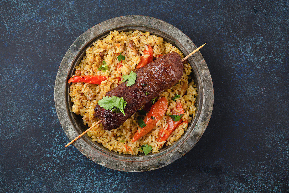 Traditional Middle Eastern meat Kebab with rice in rustic metal plate