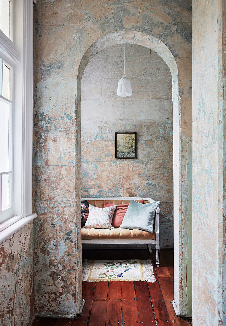 View through round arch onto sofa in winter garden