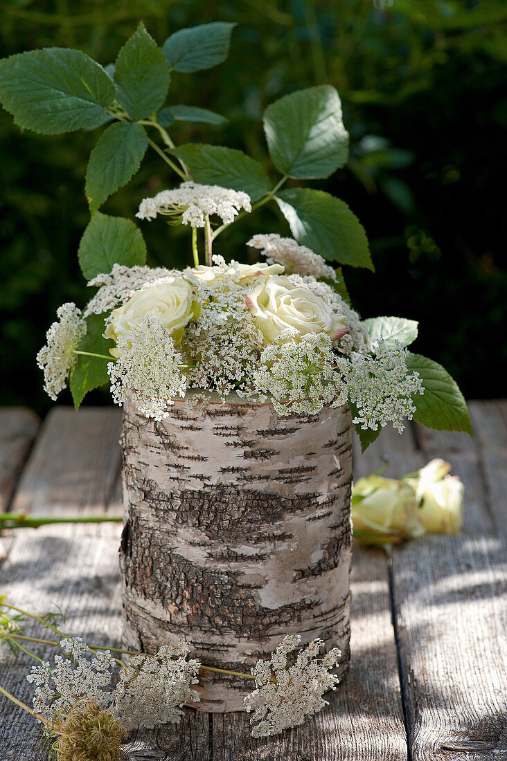 Bouquet of roses and Queen Anne's lace in vase made from birch branch