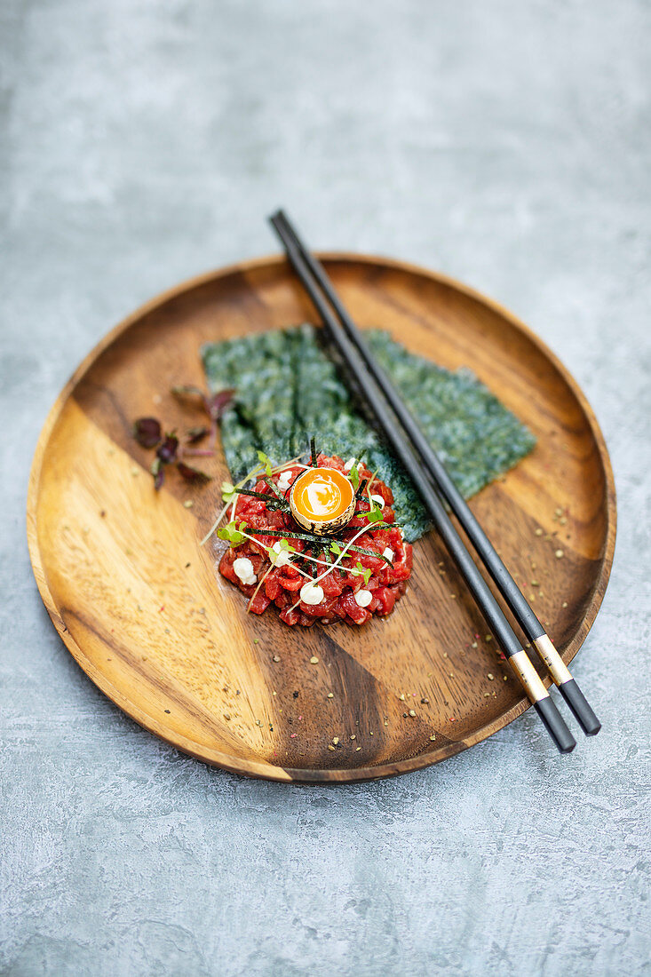 Wagyu-Tartar serviert mit Wachtelei und Algenblättern (Japan)