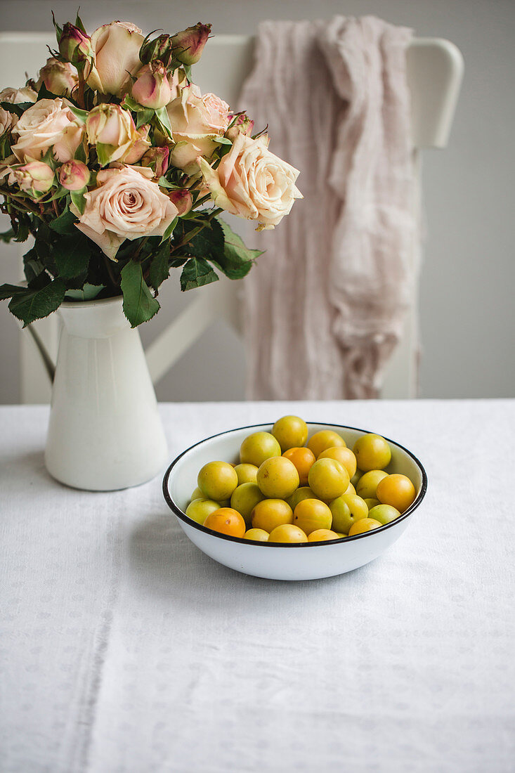 Green plums in a bowl on a kitchen table