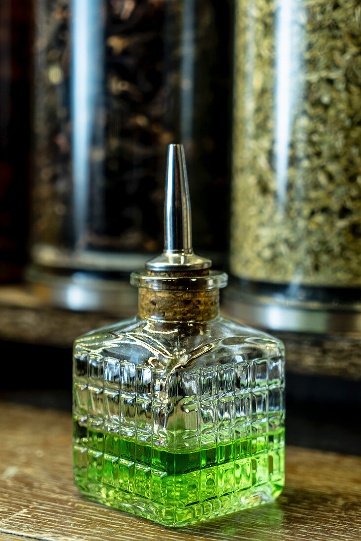 Glass bottle of green absinthe with dispenser in retro pub