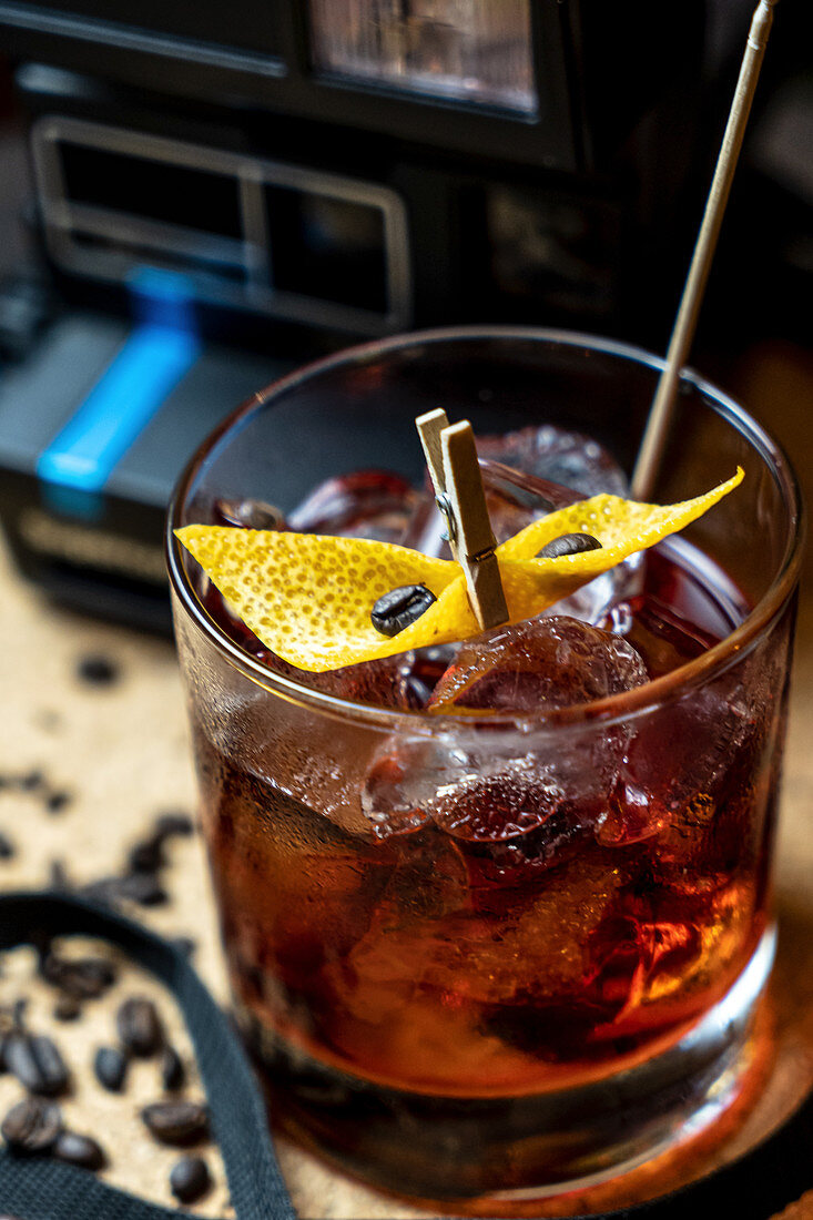 Cocktail mit Orangenschale, Eiswürfeln und Kaffeebohnen in einer Bar