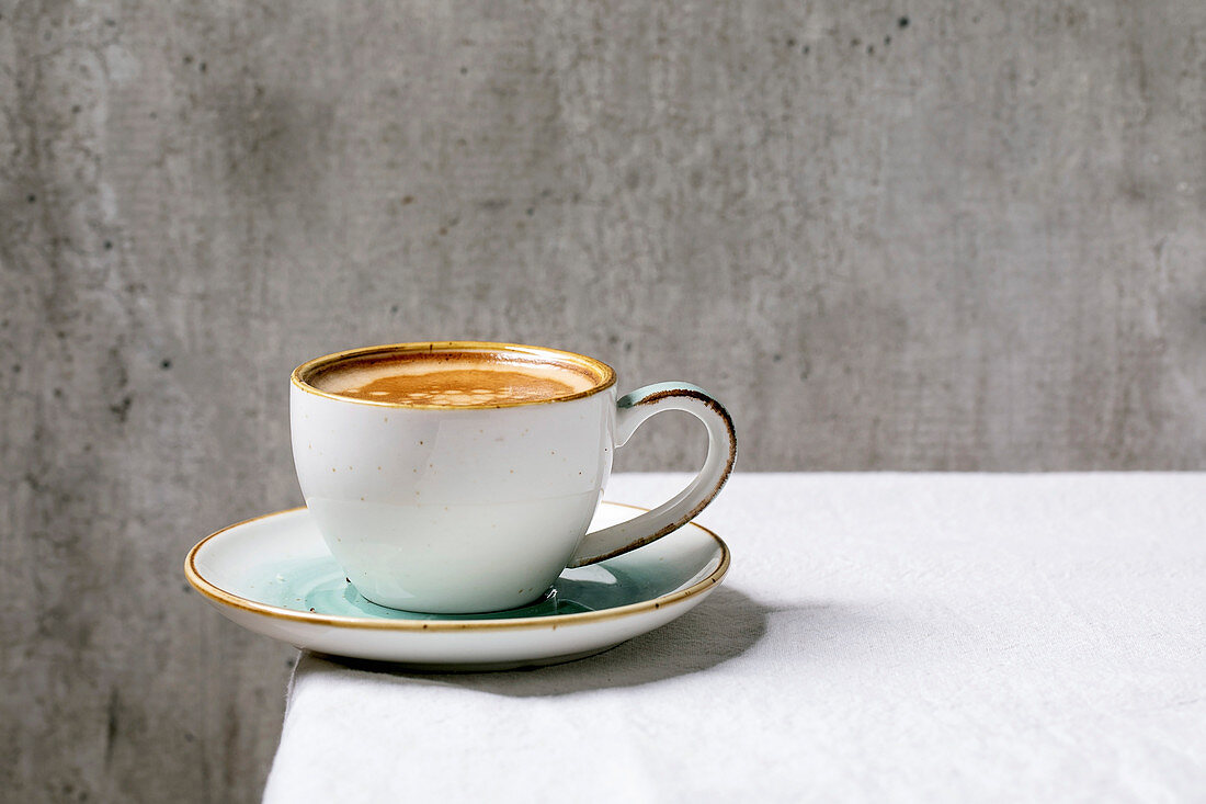 Eine Tasse Kaffee auf Tisch vor grauem Hintergrund