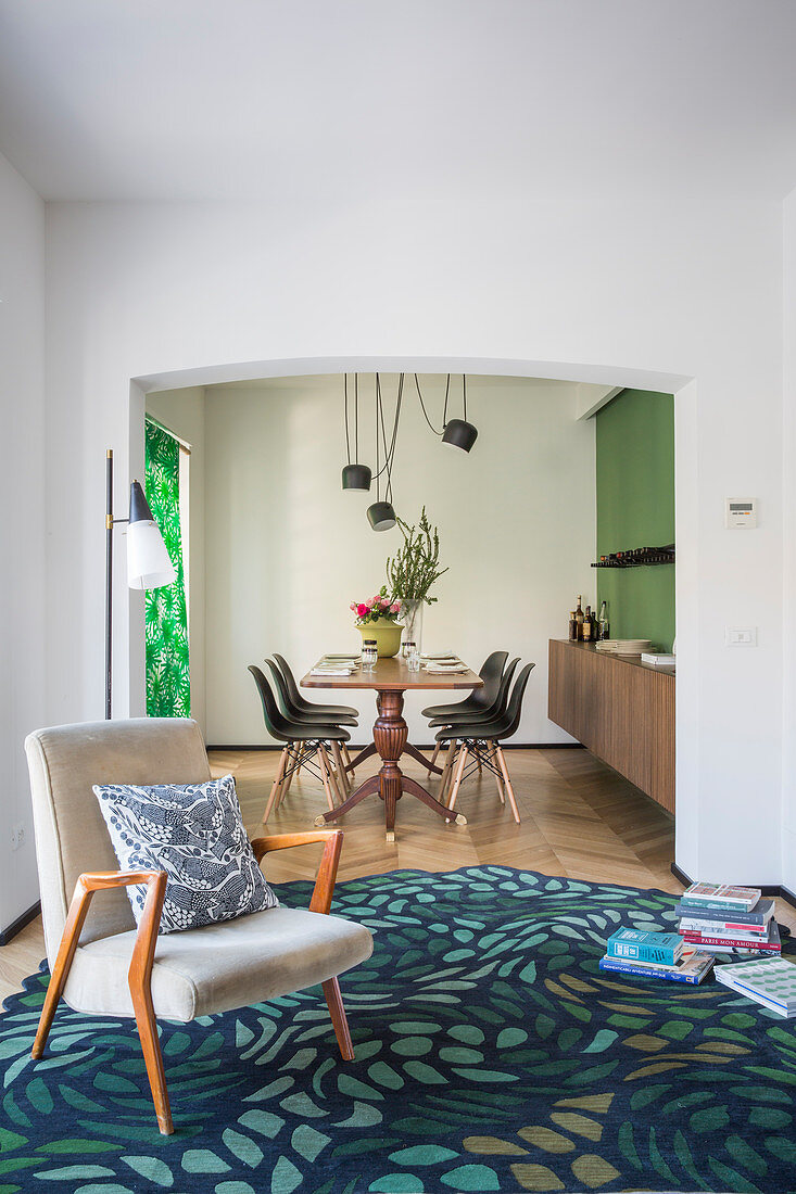 Armchair on patterned rug in front of open doorway leading into dining room