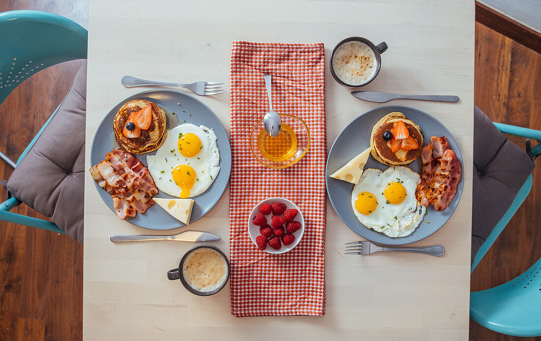 Frühstück mit Pancakes, Spiegeleiern, Bacon und Käse