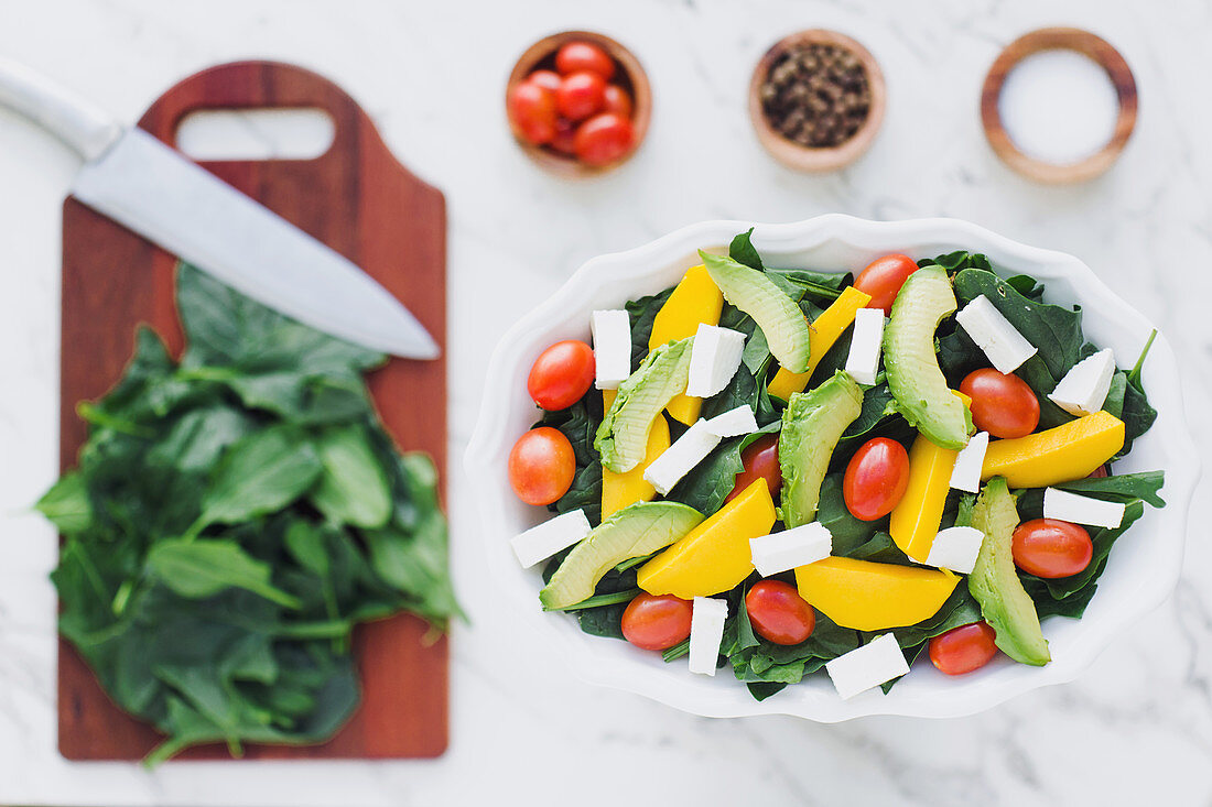 Spinach salad and mix of pumpkin and avocado with cherry tomatoes topped with feta cheese