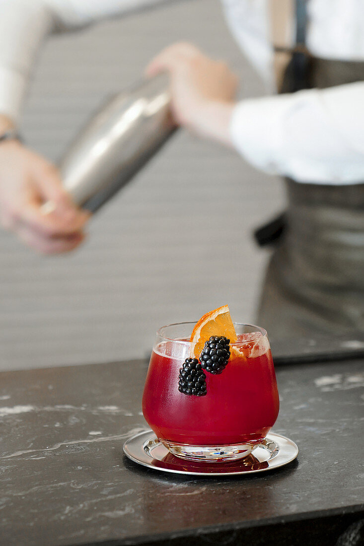 Glass of red refreshing cocktail with orange slice and blackberries