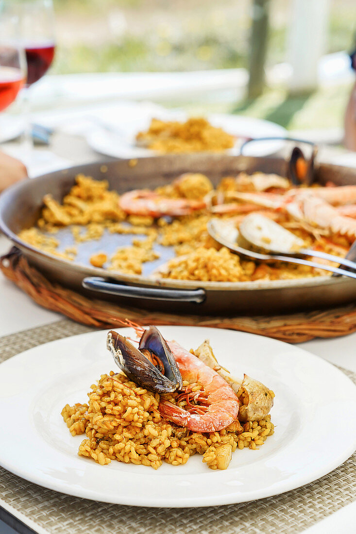 Pan with arroz marinero served on table with plates and fresh drinks
