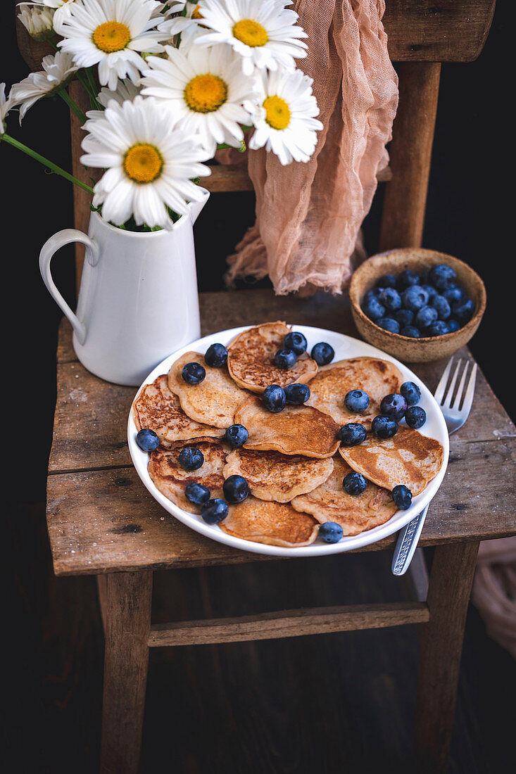 Bananen-Pancakes mit Blaubeeren auf rustikalem Holzstuhl