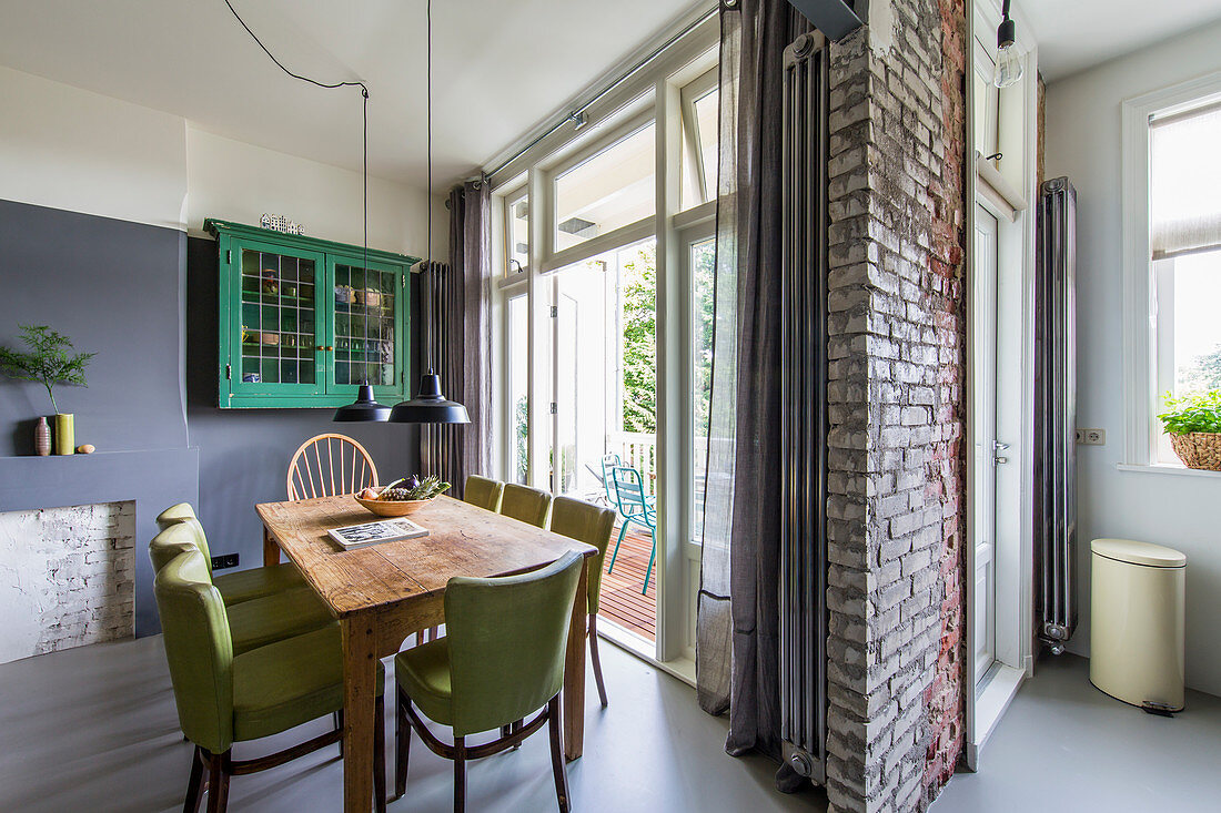 Wooden table and green chairs next to balcony doors