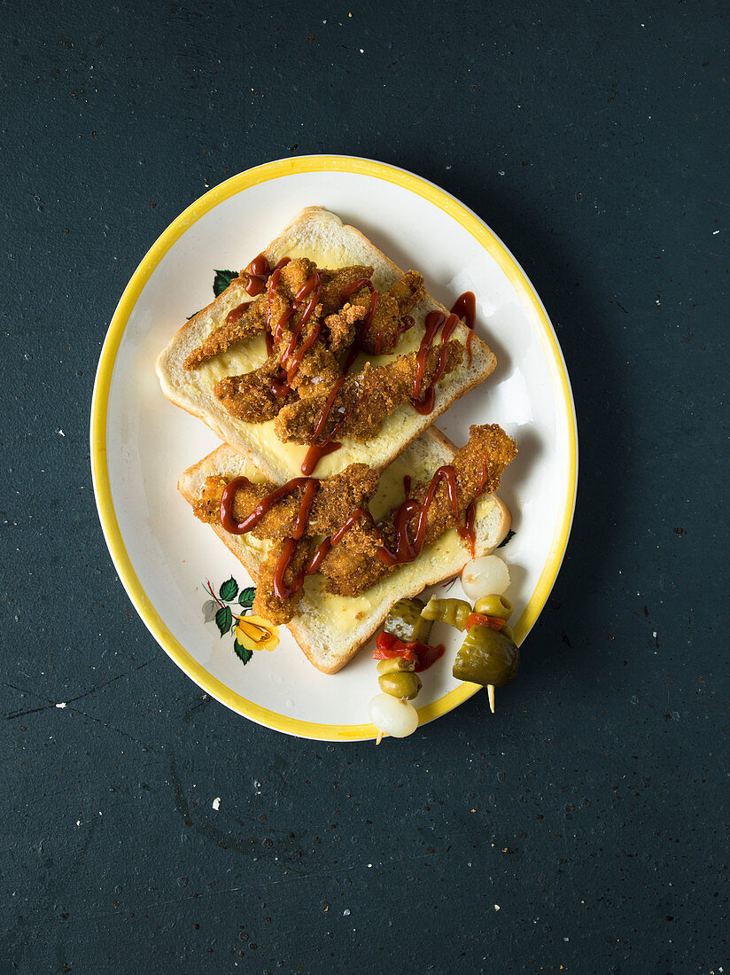 Knusprig gebratene Schweineohren auf Toastbrot mit Gurkenspießchen