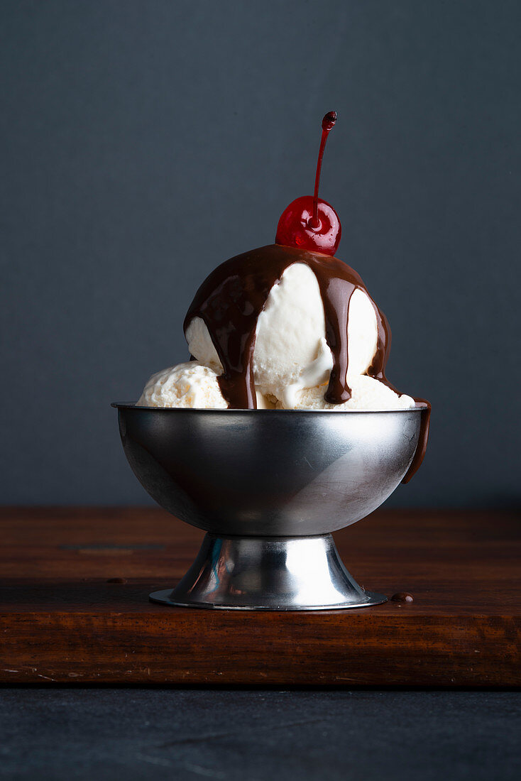 Vanilleeis mit Schokoladensauce und Belegkirsche im Eisbecher