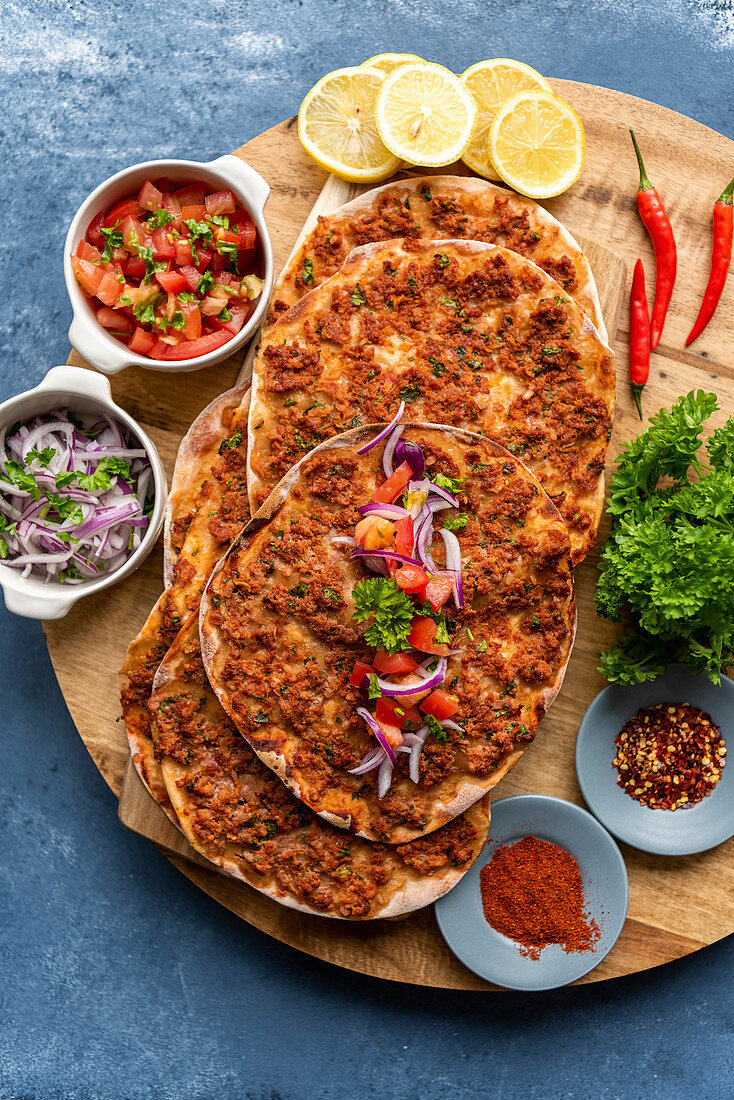Homemade Turkish lahmacun served with red onion salad and tomato salad as condiments