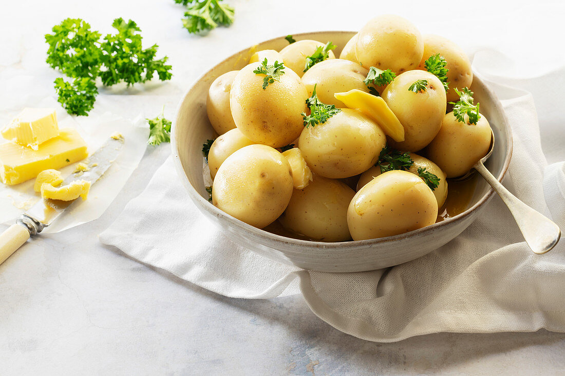 Gedämpfte Pellkartoffeln mit Butter und Petersilie in Keramikschale