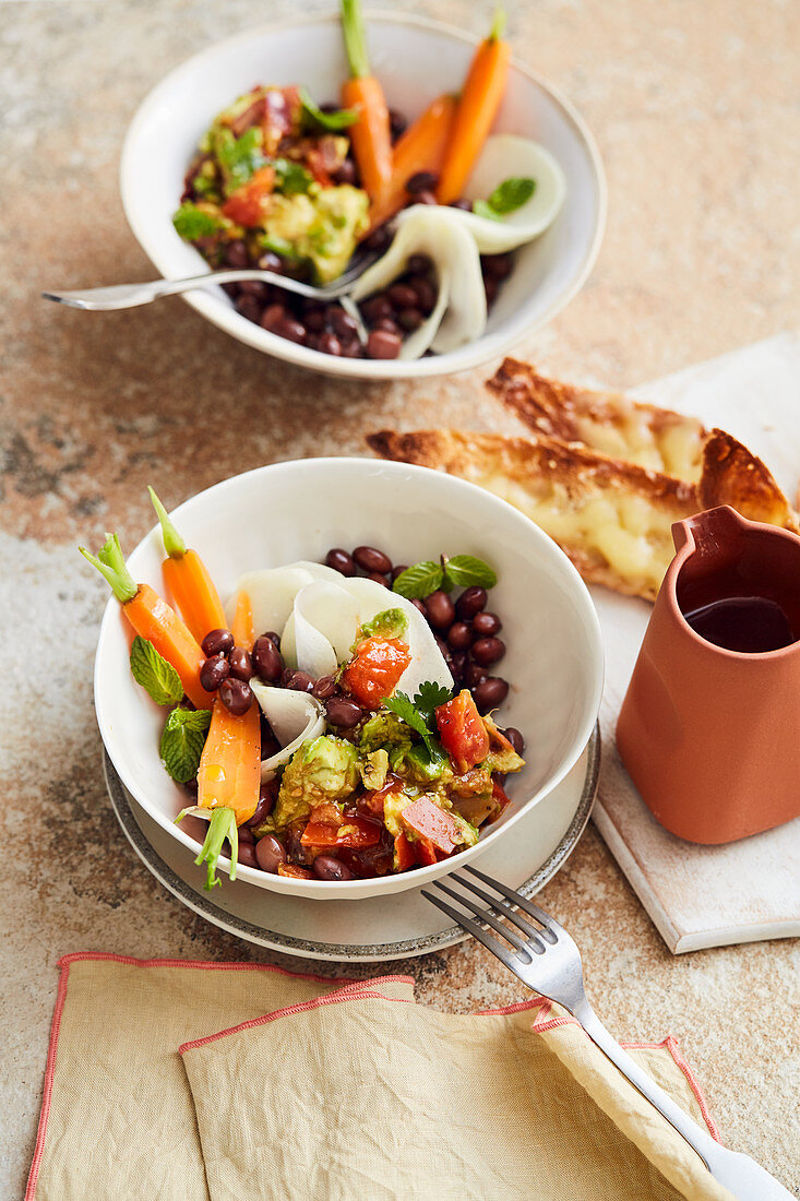 Tomatoes with mashed avocado and beans served with Gruyere crostini