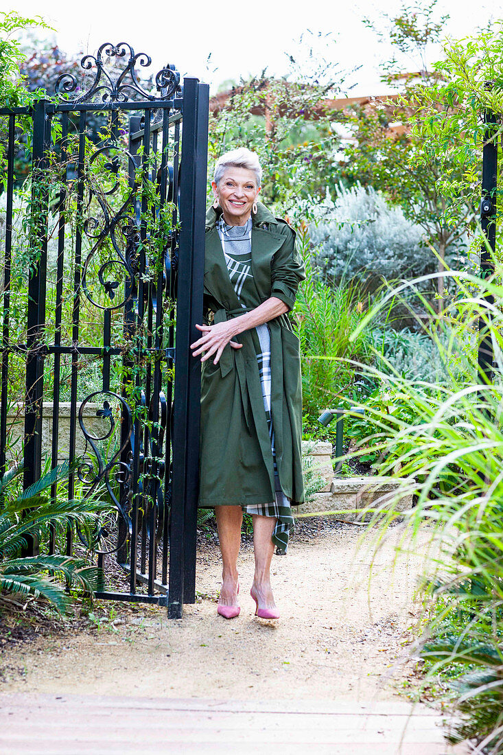 A grey-haired woman wearing a green checked dress and a green coat